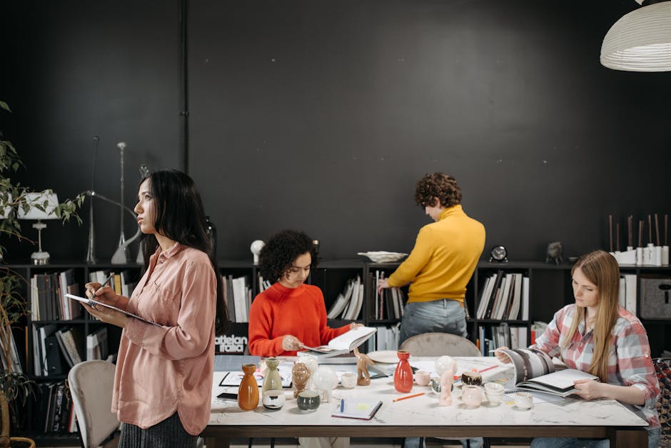 A group of adults engaged in creative work and discussion around a table in an office setting.